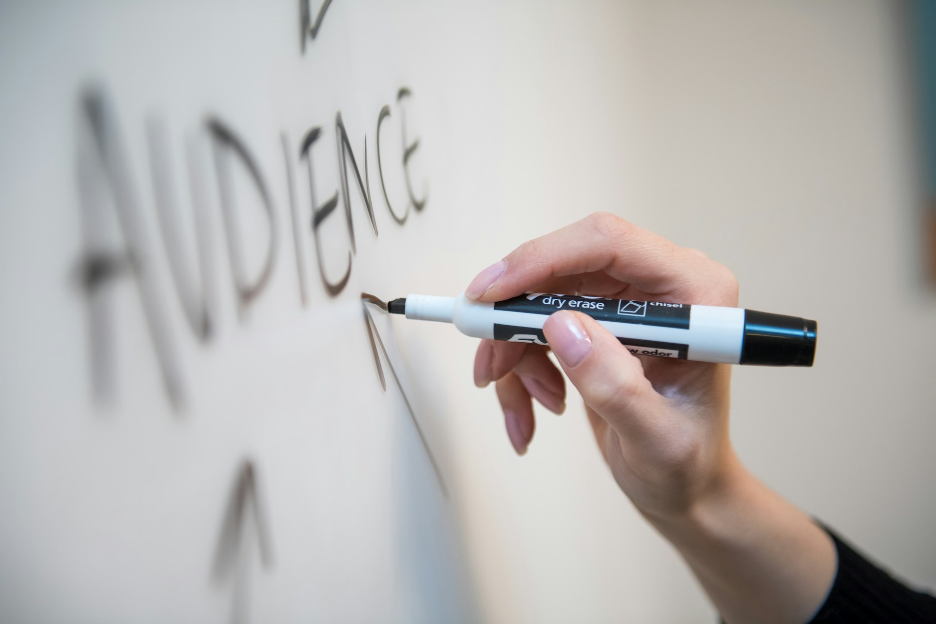 Hand writing the word "audience" with an arrow on a whiteboard